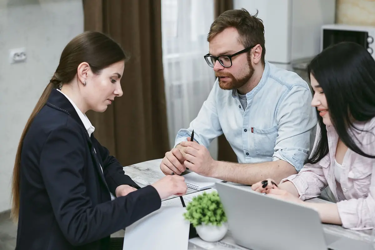 Two JE Auto staff going through paperwork with a customer at the sales desk