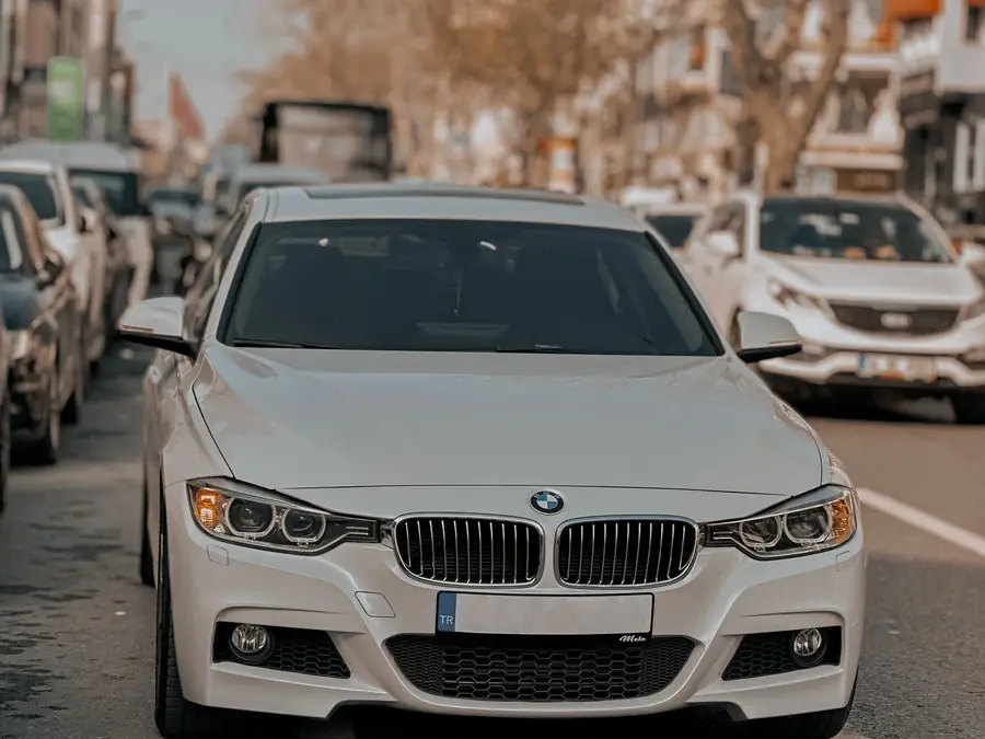 White BMW 320i Sport seen head-on in city traffic