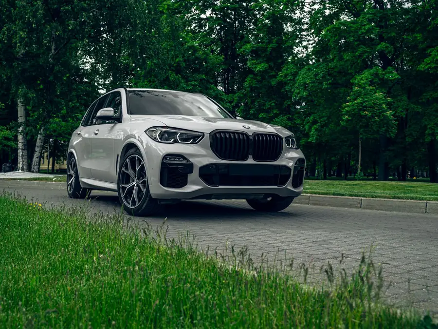 White BMW X5 xDrive40i parked on a paved drive beside a treeline