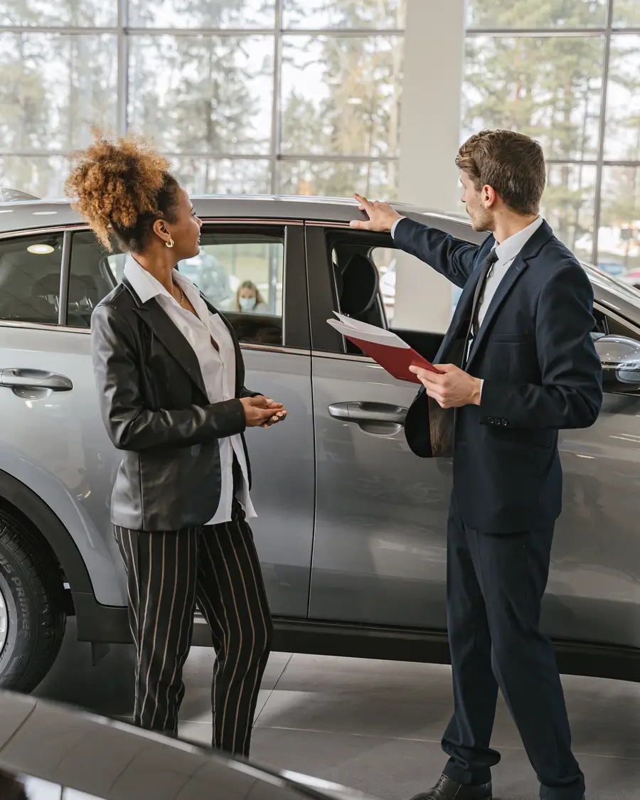A salesperson walking a customer around a car on the JE Auto forecourt