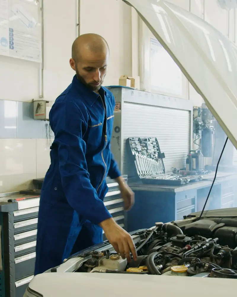 A technician working through an engine bay with the bonnet raised