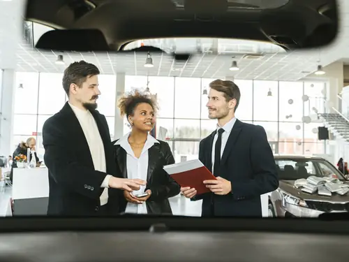 Three people finalising a car purchase at the JE Auto sales desk