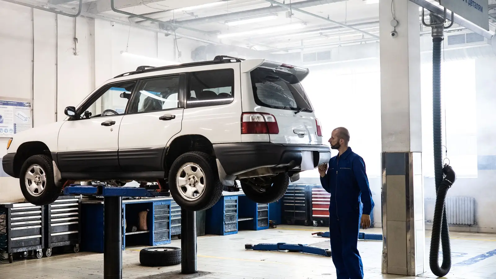 A vehicle raised on a two-post lift in the JE Auto inspection bay
