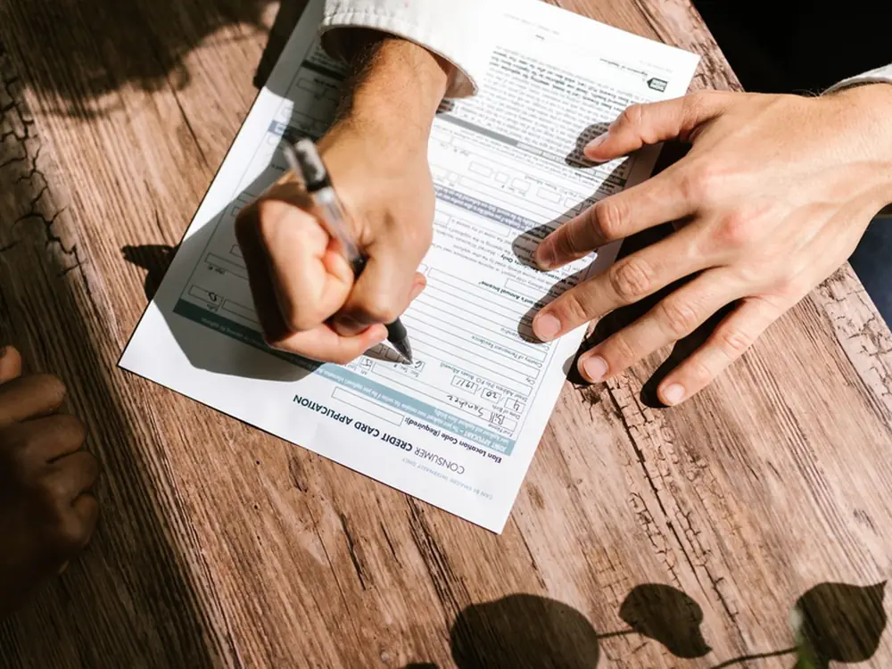A hand filling in a vehicle hire purchase application form